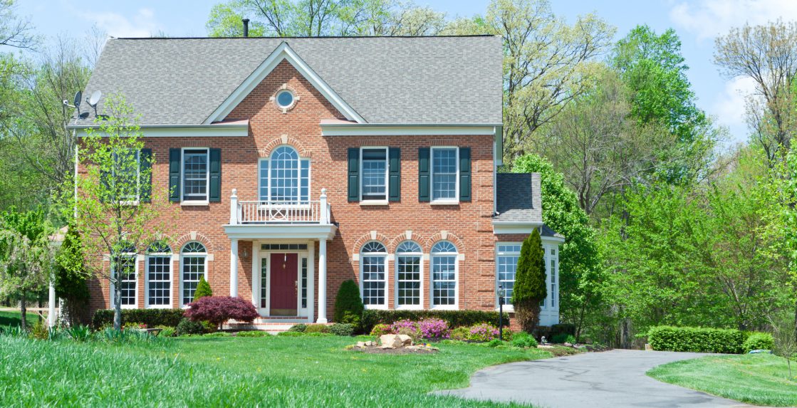 Tidy Colonial Style single family house in suburban Maryland, United States.  House is brick faced and has a long curvy driveway.
